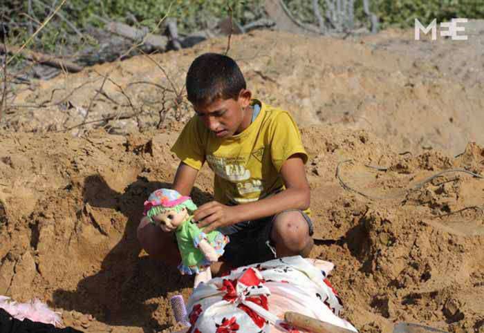 (ภาพ) เด็กชายคนหนึ่งถือตุ๊กตาของราฮัฟ ฮัซซัน หนูน้อยวัยสามขวบที่เสียชีวิตจากการโจมตีทางอากาศของอิสราเอลเมื่อวันอาทิตย์ พร้อมกับแม่ของเธอ (MEE/Mohammad Asad)